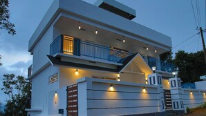 Une maison moderne à deux étages, dotée d’un balcon, d’un escalier et d’une entrée bien éclairée.
