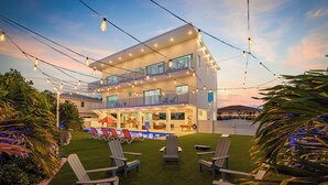 Un bâtiment à deux étages doté d’un espace piscine, de coins salon extérieurs et de guirlandes lumineuses.