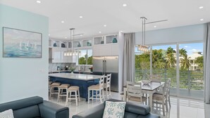Une cuisine moderne dotée d’un îlot central, de tabourets de bar et d’un coin repas avec une table et des chaises.