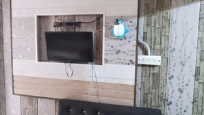 Televisão de tela plana fixada na parede, com tomada e organização de cabos.