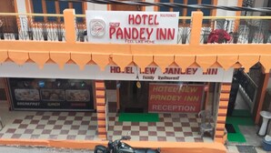 Um hotel chamado 'Hotel New Pandey Inn' com uma placa indicando que oferece café da manhã, almoço e jantar.