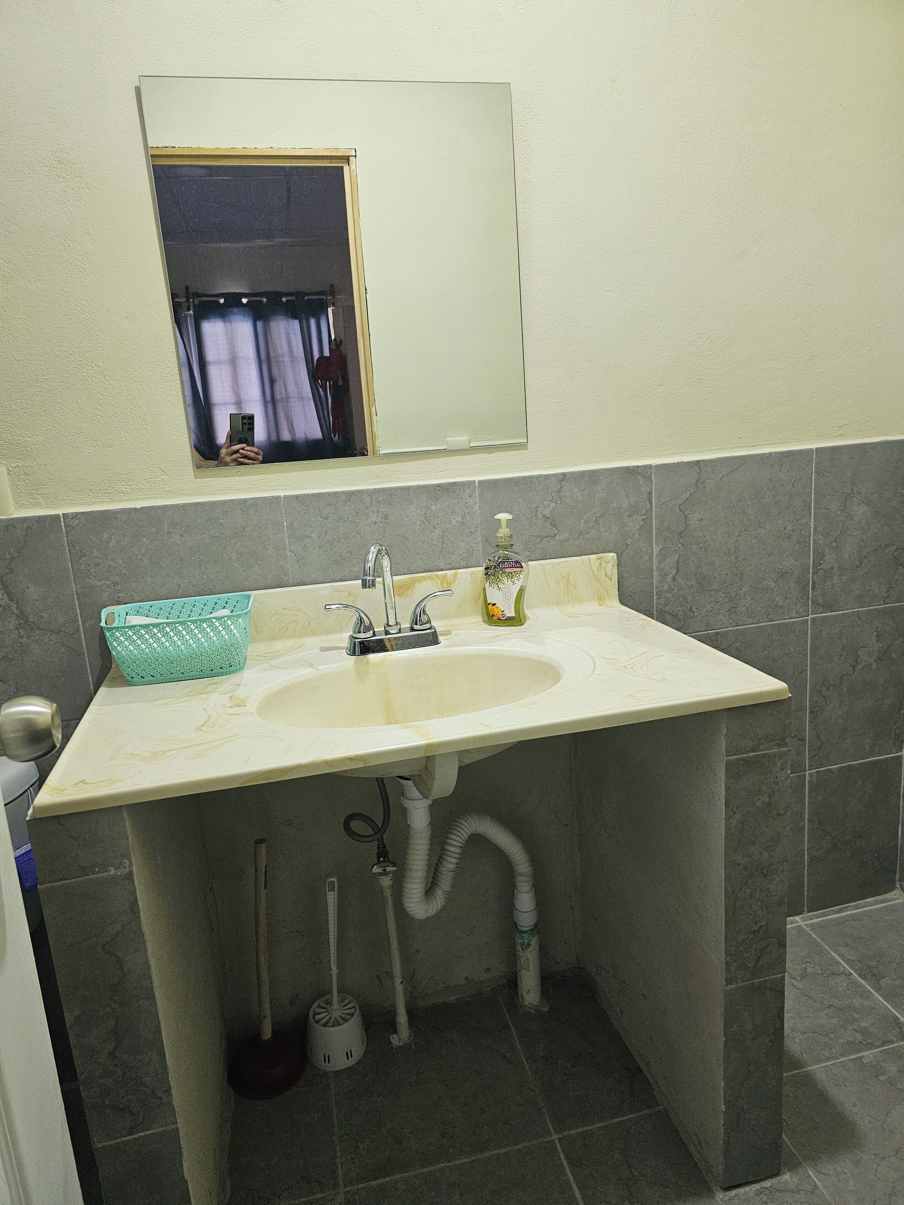 A bathroom with a sink, mirror, and a window above it.