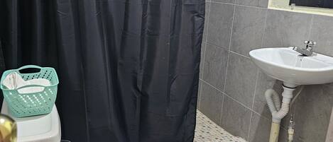 A bathroom with a toilet, a sink, a shower curtain, and a tiled floor.