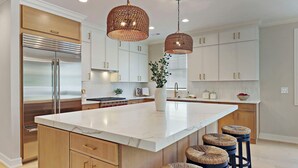 A modern kitchen with a large island, stainless steel appliances, and wicker bar stools. - NEW LUXURY Condo - Walk to The Abbey! Sleeps 10! Fontana-on-Geneva Lake (Fontana-on-Geneva Lake)