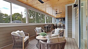 A covered outdoor seating area with wicker furniture, large windows, and ceiling fans. - NEW LUXURY Condo - Walk to The Abbey! Sleeps 10! Fontana-on-Geneva Lake (Fontana-on-Geneva Lake)