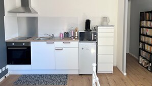 Kompakti keittiö, jossa on mikroaaltouuni, kahvinkeitin ja pieni jääkaappi.