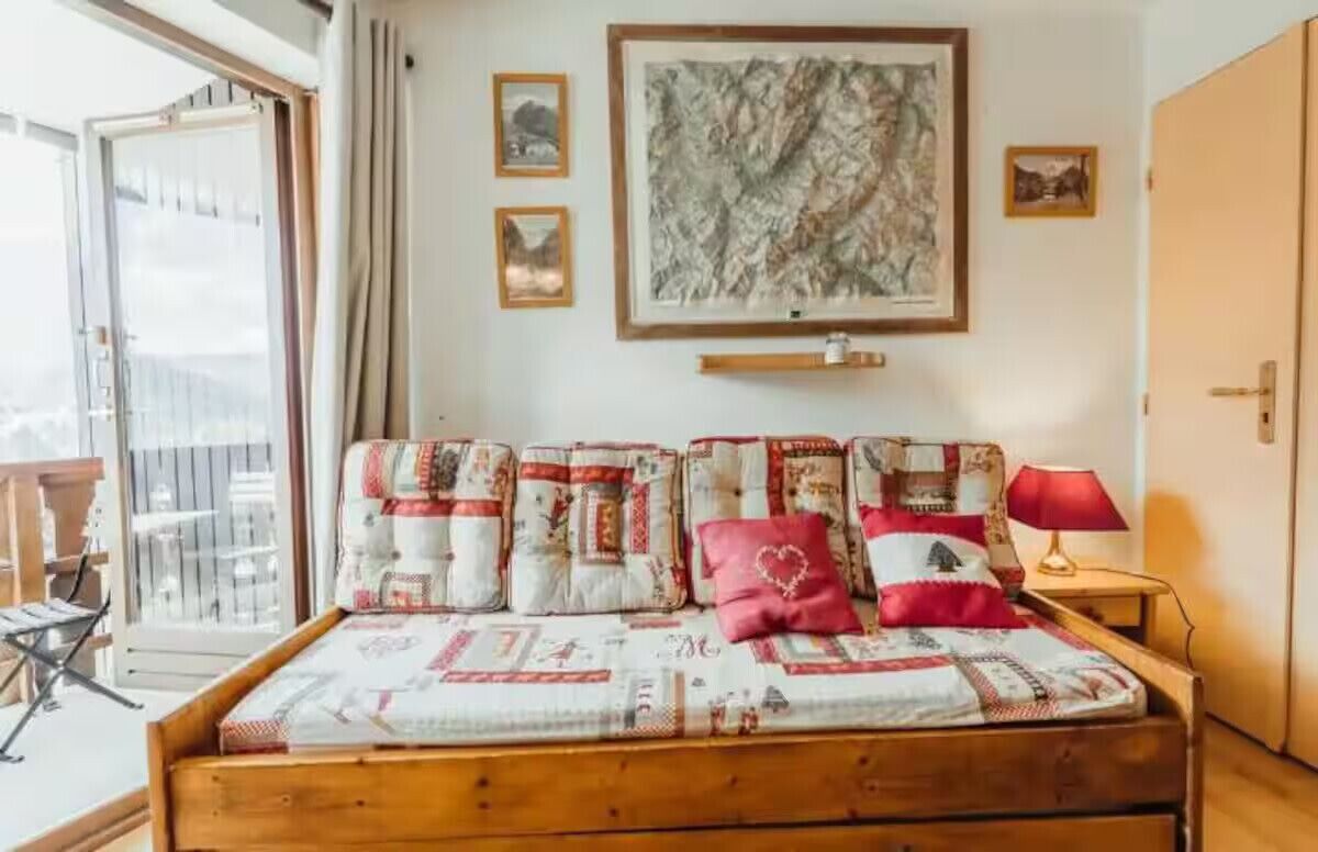 A bed with a quilt, a red lamp, and a framed map on the wall.