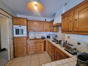 Una cocina con armarios de madera, microondas, tostadora y lavabo.