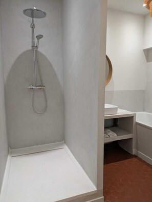 Ein Badezimmer mit Dusche, Waschbecken und Spiegel.