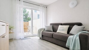 Een moderne woonkamer met een bank, een tafeltje met een plant en een glazen schuifdeur naar een terras.