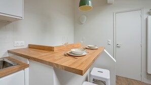 A kitchen with a wooden countertop, two pendant lights, a white door, and a white stool. - Bright Studio at Nation, Paris 12th (Paris)
