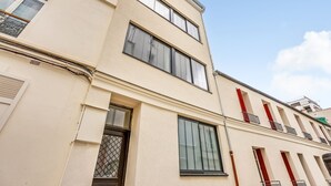 A multi-story building with a flat facade, large windows, and a door with a metal grille. - Bright Studio at Nation, Paris 12th (Paris)