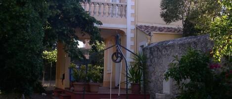 A building with a stone well, a balcony, and potted plants.