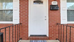 A red brick house with a white door, a mailbox, and a welcome mat. - Furnished 3BR Corporate Rental in Petersburg (Petersburg)