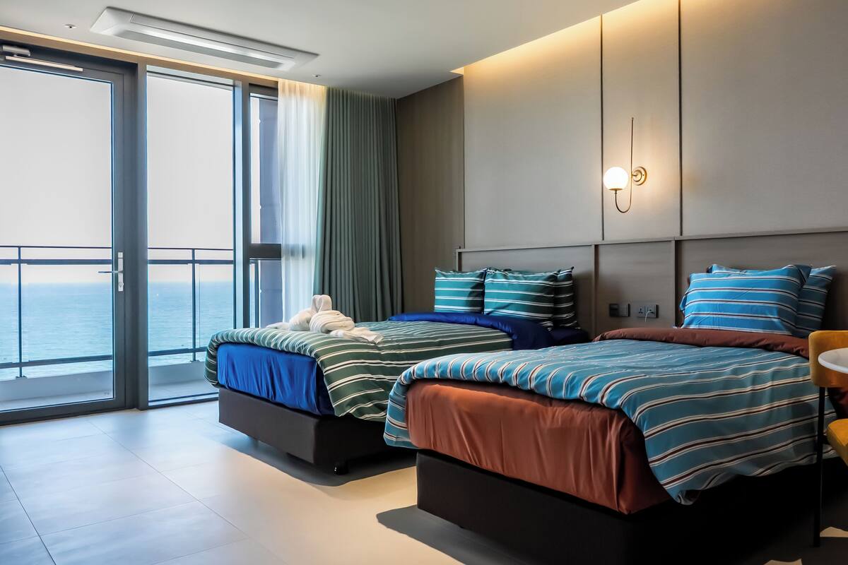 Ein modernes Hotelzimmer mit zwei Betten, einem Balkon mit Blick und einem kleinen Tisch.