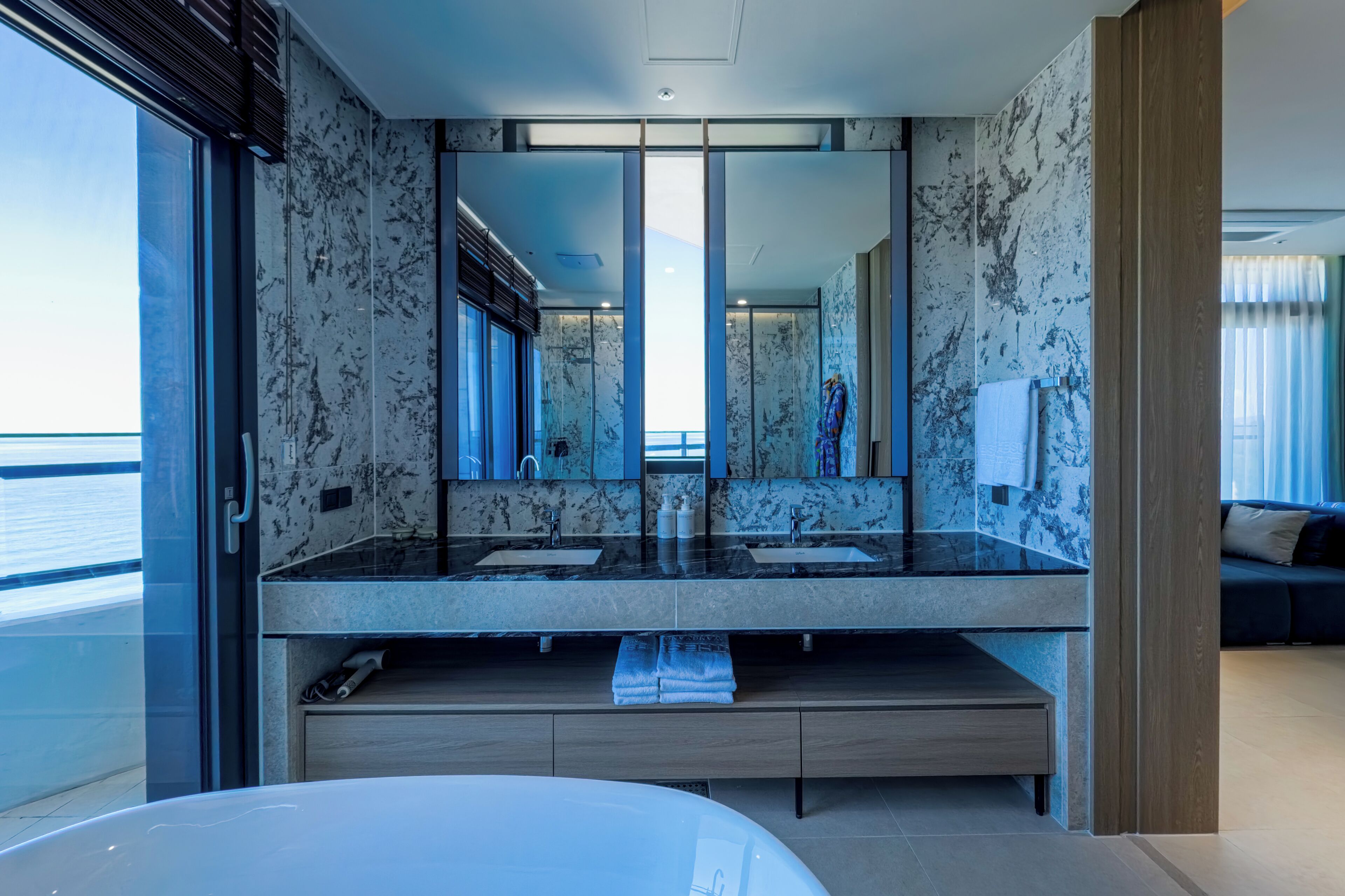 Un baño moderno con un espejo grande, dos lavamanos y una bañera.