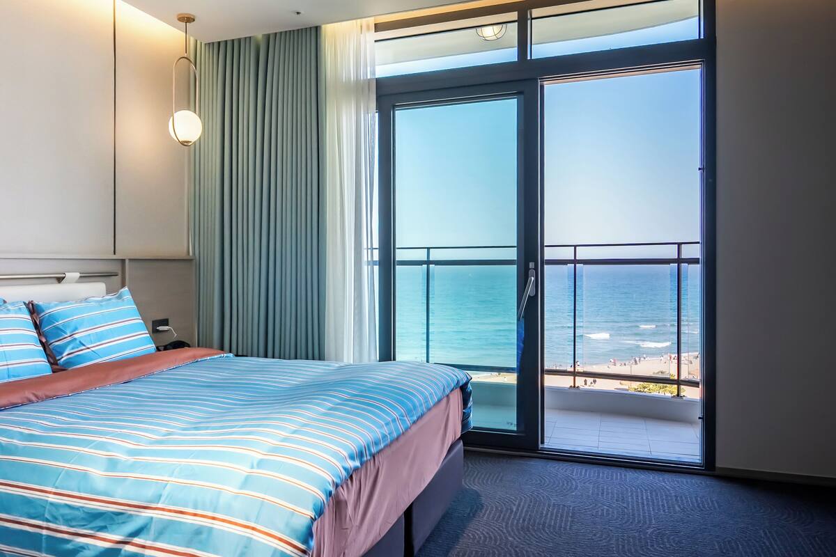 Ein Hotelzimmer mit Bett, Fenster mit Meerblick und Balkon.