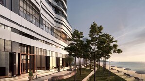 A modern hotel with a curved facade, outdoor seating, and a view of the ocean. - St. The Suite Yangyang (Yangyang)