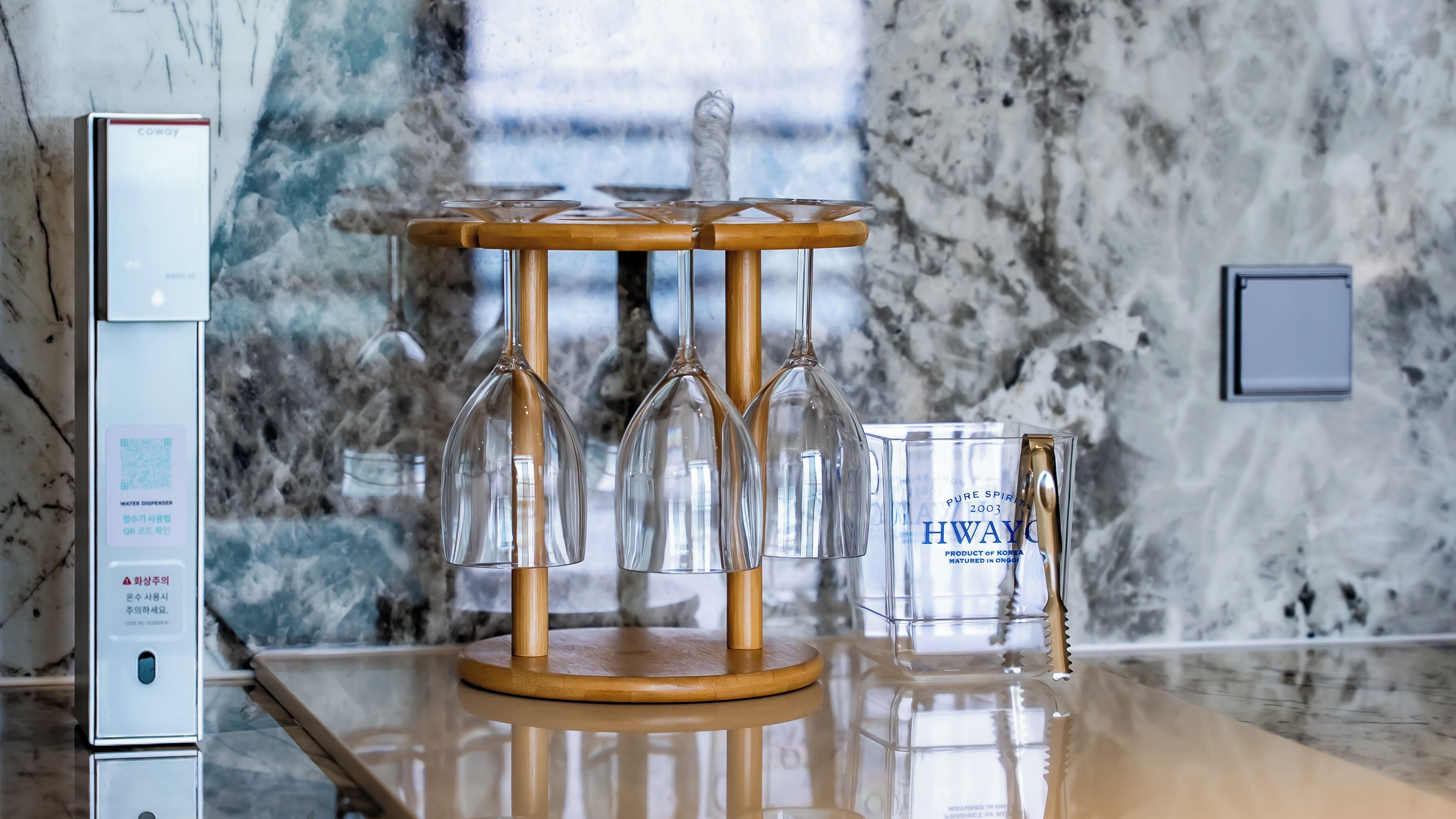 Un distributeur d’eau et un porte-verres contenant plusieurs verres, le tout posé sur un comptoir en marbre.