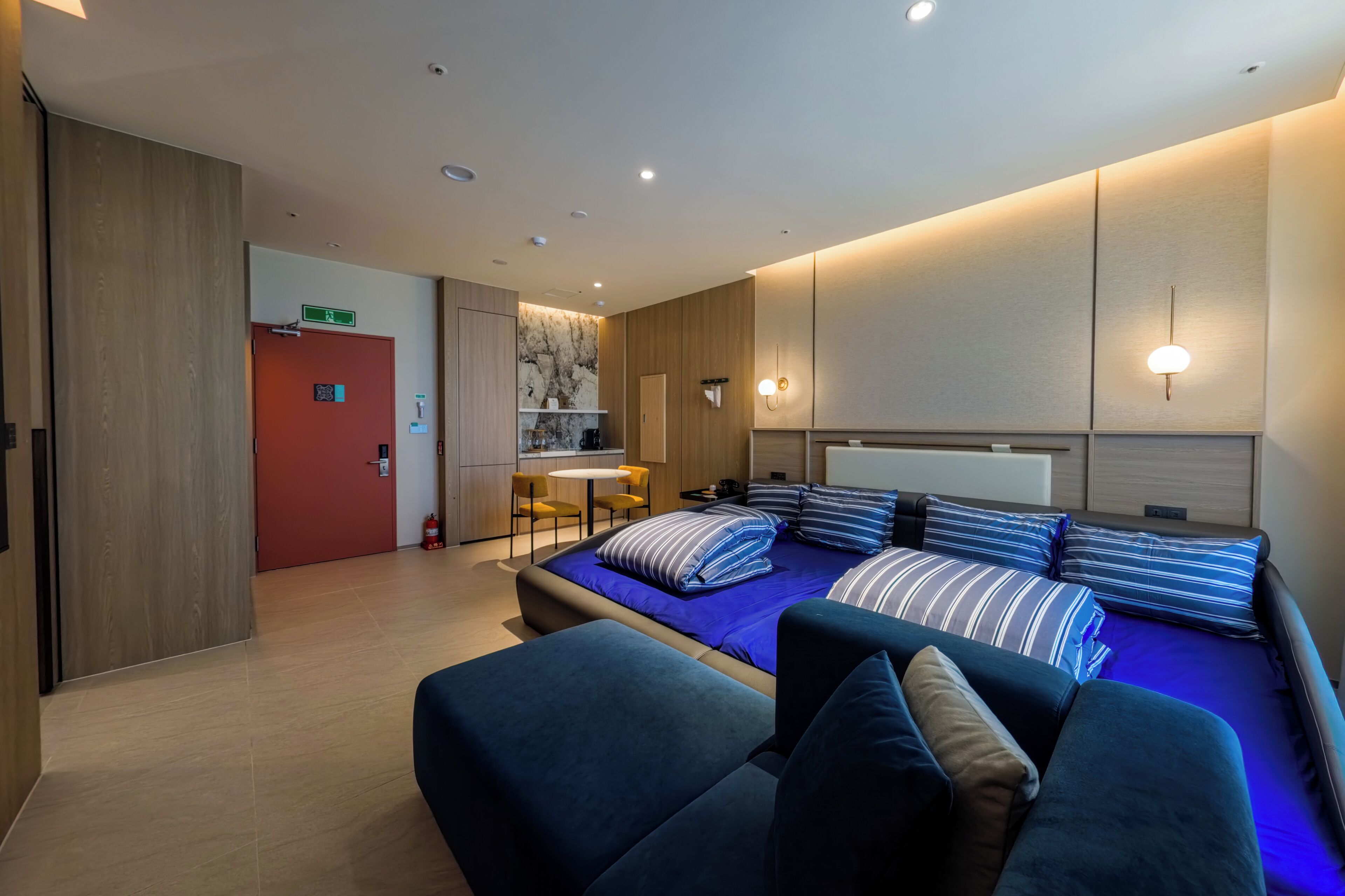 Una habitación de hotel moderna con una cama, un sofá, una kitchenette pequeña y un baño.