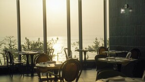 A restaurant with outdoor seating, tables, chairs, and a view of the sea. - St. The Suite Yangyang (Yangyang)