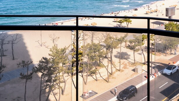 A beach view from a window with a clear sky, sandy beach, and a few trees. - St. The Suite Yangyang (Yangyang)