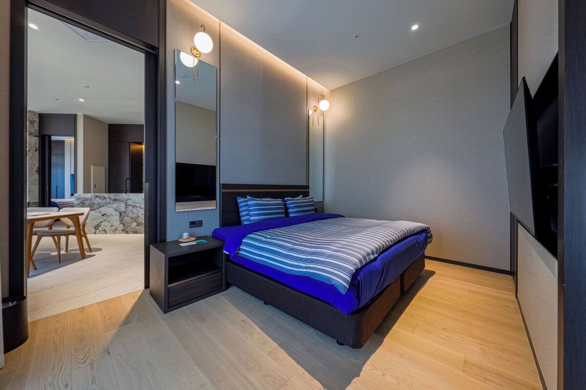 Ein modernes Schlafzimmer mit Bett, Nachttischen, einem Spiegel und einem Fernseher.