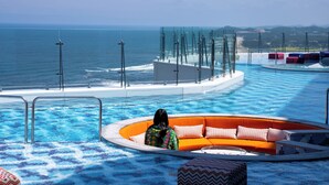 A pool area with a circular seating area and a glass barrier overlooking the ocean. - St. The Suite Yangyang (Yangyang)