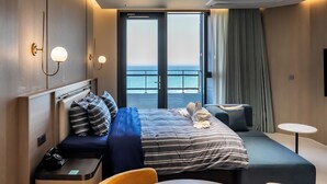 A hotel room with a bed, bedside tables, a seating area, a small table, and a view of the sea. - St. The Suite Yangyang (Yangyang)