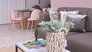 Una sala de estar moderna con un sofá, una mesa de centro, una mesa de comedor con sillas y un jarrón decorativo.