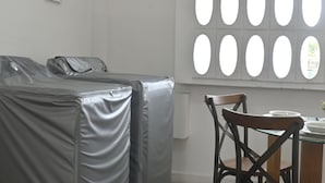 Una habitación con un sofá tapizado, una mesa de comedor con sillas y un ventanal con formas ovaladas.