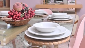 Un comedor con una mesa de vidrio, sillas rosadas y un espejo grande en la pared.