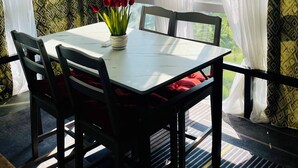 Ein Essbereich mit Tisch, Stühlen und einer Vase mit roten Blumen.