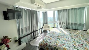 Ein modernes Hotelzimmer mit einem großen Bett, einem an der Wand montierten Fernseher und einem Balkon mit Vorhängen.