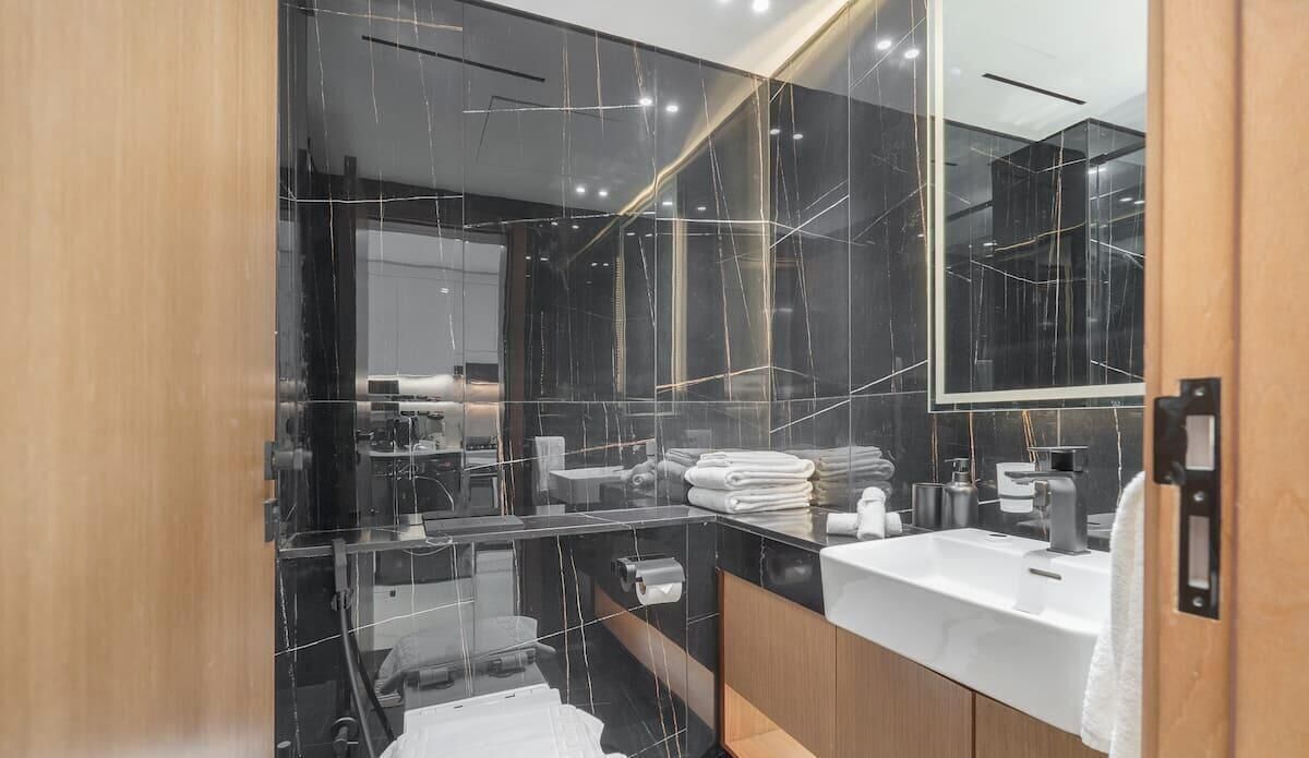 Un baño moderno con cabina de ducha de vidrio, tocador con lavabo y un espejo grande.