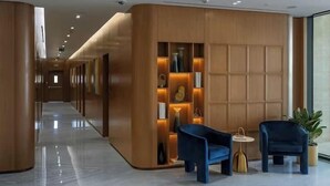 A modern hotel lobby with a long corridor, wooden paneling, and a seating area with two blue chairs and a small table. - Vogue | Binghatti Galaxy JVC near Circle Mall (Dubai)