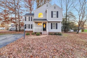 A two-story house with a porch, a front door, and a small circular window above the door. - MidTerm Housing  Utilities Included Move-In Ready (Prince George)