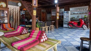 Una habitación con techo de madera, una motocicleta roja, un sofá con cojines estampados y piso de baldosas.