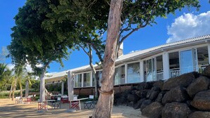 A beachfront property with a covered patio area, outdoor seating, and a stone wall. - Azuri Resort Villa: Pool, Golf & Beach Club (Rivière du Rempart)