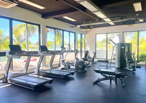 Ein Fitnessstudio mit Laufbändern, Crosstrainern und Gewichtsbänken.