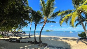 A beach with palm trees, a sandy shore, and a clear blue sky. - Azuri Resort Villa: Pool, Golf & Beach Club (Rivière du Rempart)