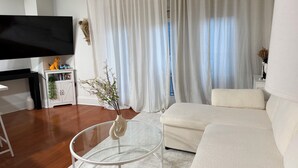 Ein modernes Wohnzimmer mit einer Couch, einem Glastisch, einem Flachbildfernseher und einem Bücherregal.