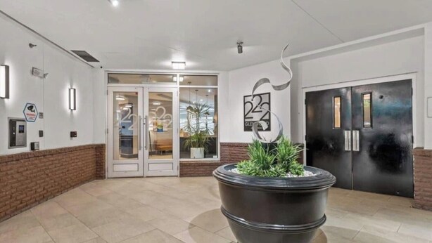 Eine Lobby mit einem großen Blumentopf, doppelten Türen und einem Schild mit einer Nummer.