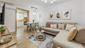 Ein modernes Wohnzimmer mit einer Couch, einem Esstisch und einer Küche im Hintergrund.