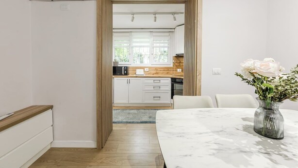Eine moderne Küche mit weißen Schränken, einer Holzausziehtheke und Blick in den Essbereich.