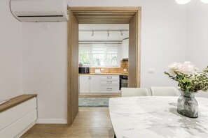 A modern kitchen with white cabinets, a wooden countertop, and a view into the dining area. - Siara Apartment by Kondo Stays (Tiranë)