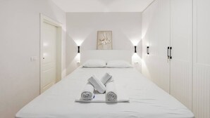 Ein Schlafzimmer mit einem Bett, zwei Nachttischen, einer Tür, einer Wandleuchte und einem Heizkörper.