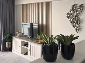 Un salon moderne doté d’un téléviseur à écran plat, d’un meuble et d’œuvres d’art décoratives accrochées au mur.