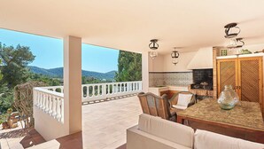 Ein geräumiger Balkon mit Bergblick, eine Essecke mit Tisch und Stühlen sowie eine Küche mit gefliestem Rücksprung.