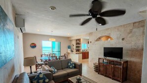 Ein Wohnzimmer mit Sofa, Fernseher und Deckenventilator.